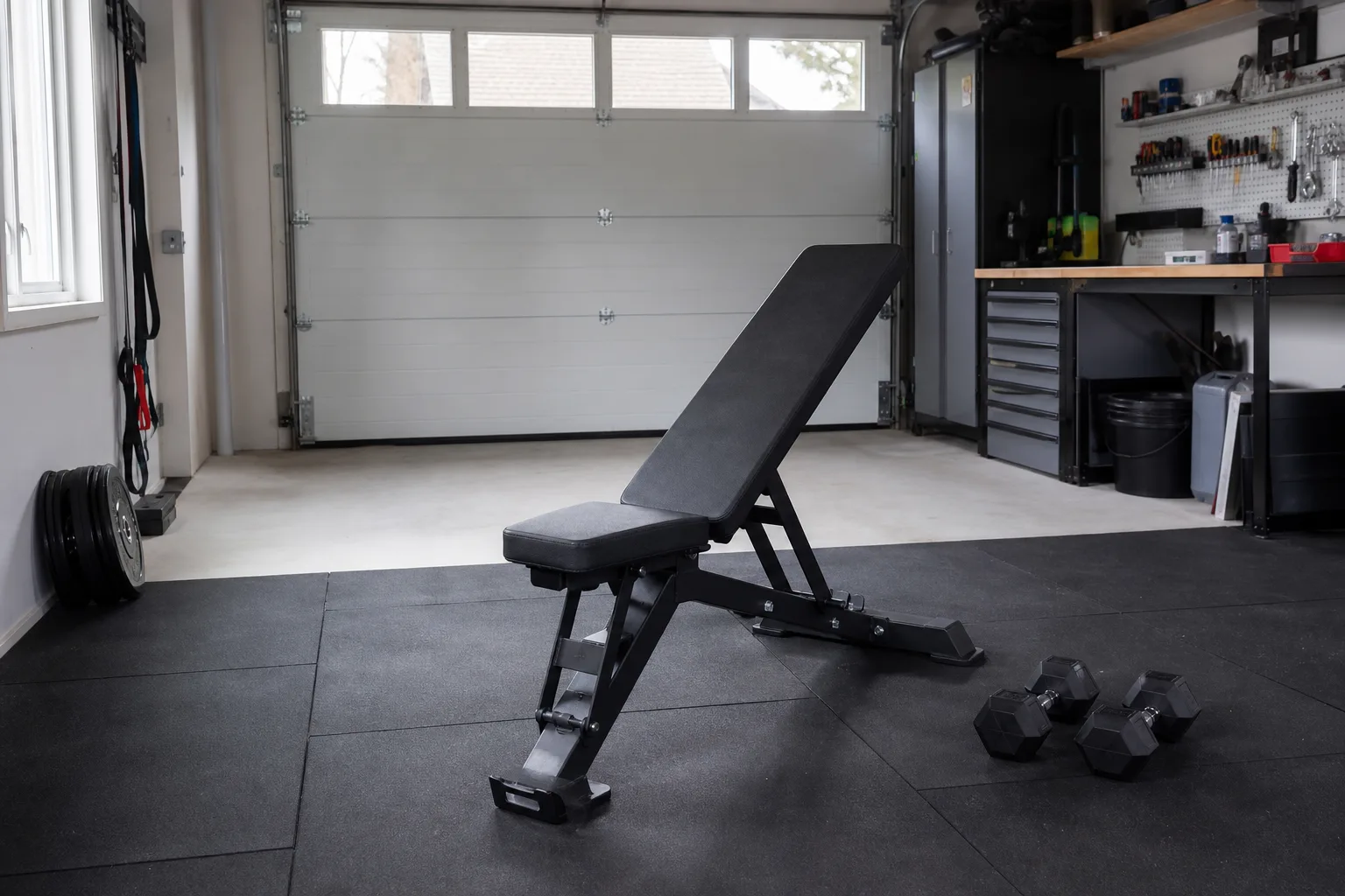 Träningsbänk på gummimatta i ett garage
